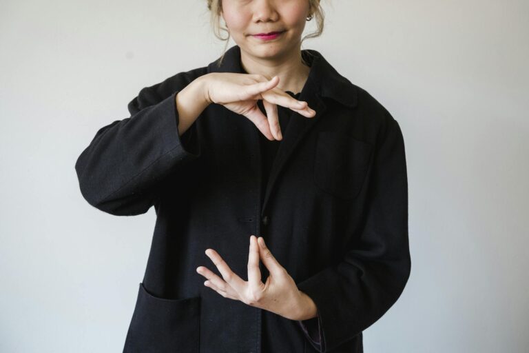 A woman in a studio using sign language against a white background.